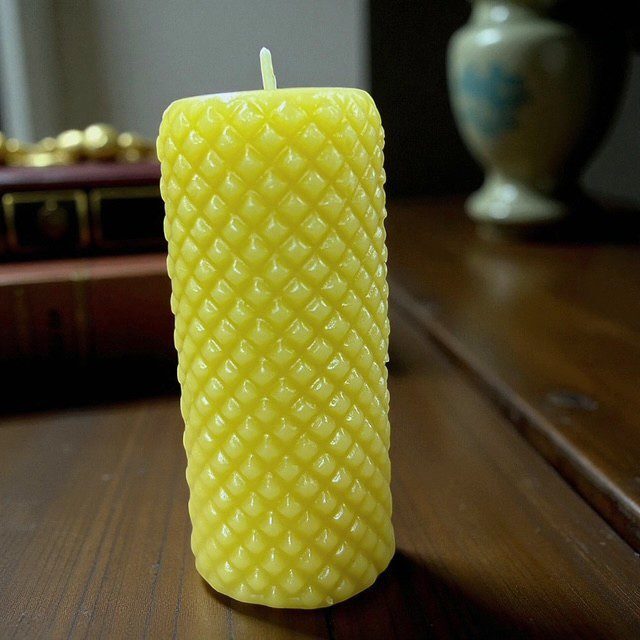 A yellow textured candle on a wooden surface.