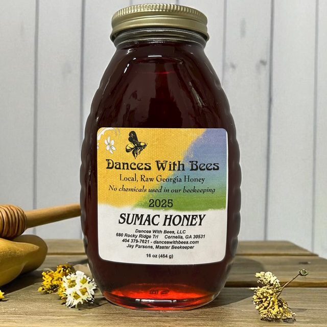 Honey jar with wooden dipper and flowers