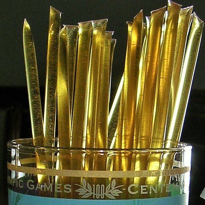 Gold commemorative drinking straws in a cup
